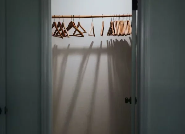 Small walk-in closet with light colors, mirrors, and strategic lighting to create a spacious feel.