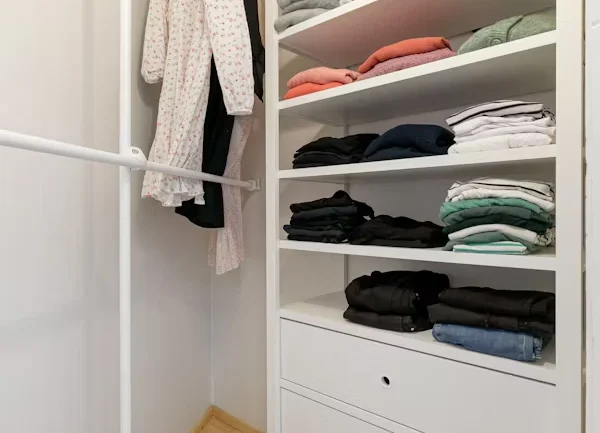 A well-organized reach-in closet with optimal depth for hanging clothes.