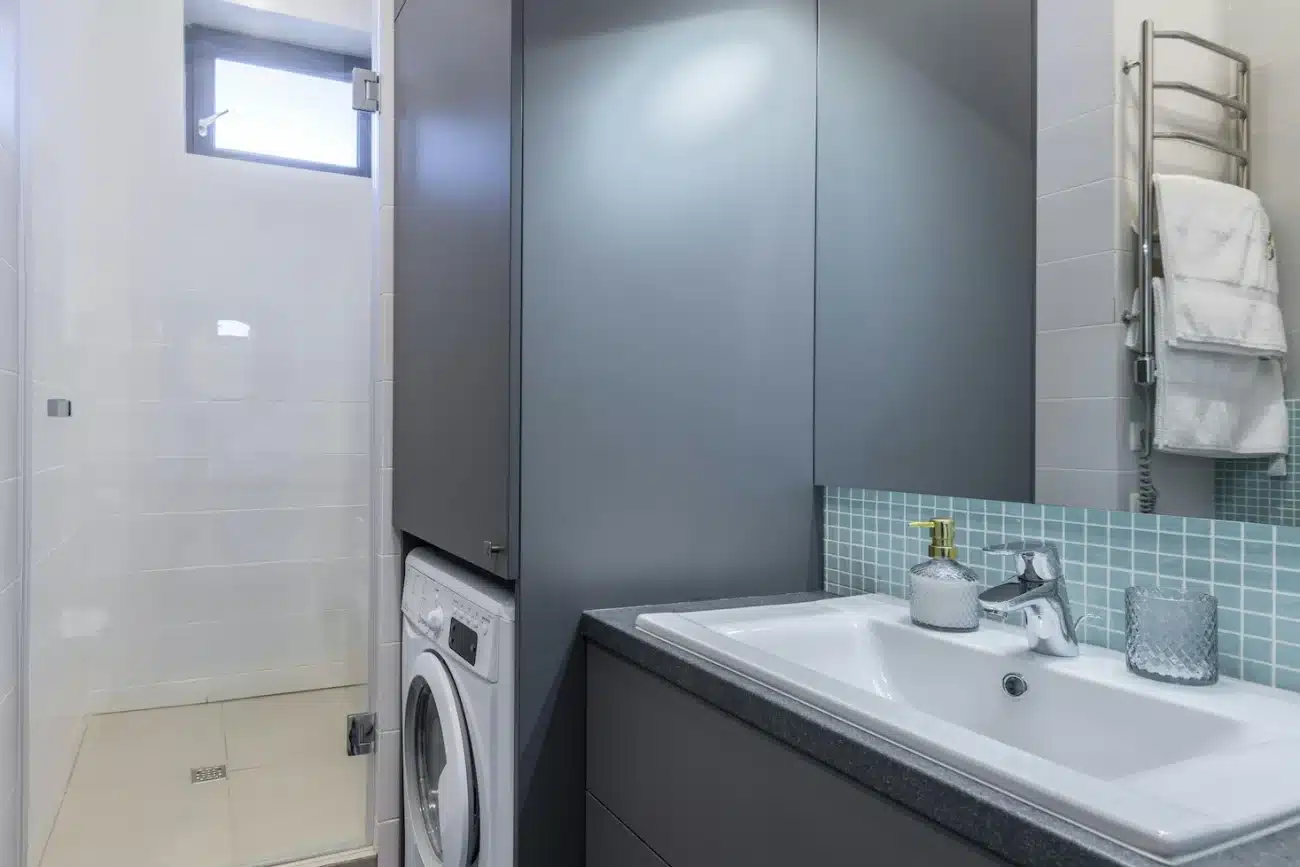 custom laundry room design for small space with vertical storage and stacked washer dryer